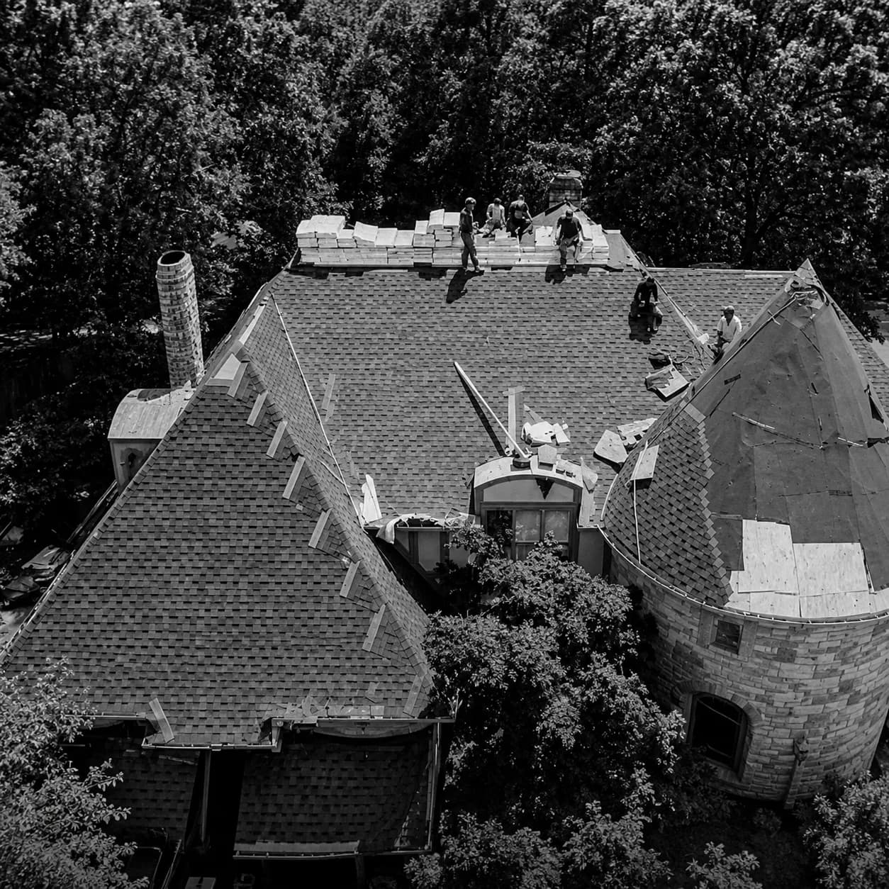Aerial view of a roofing crew re-roofing a large home