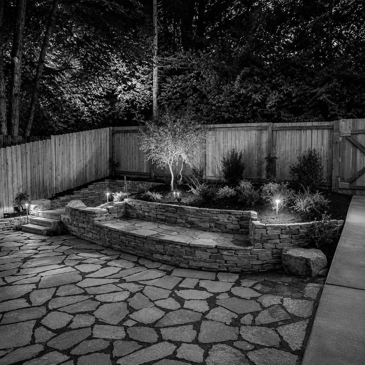 Flagstone patio with stone retaining walls and landscape lighting at dusk